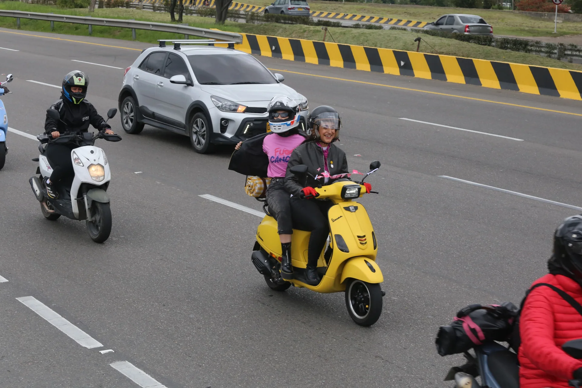 Dos mujeres comparten el camino sobre una scooter amarilla en La Ruta Rosa.
