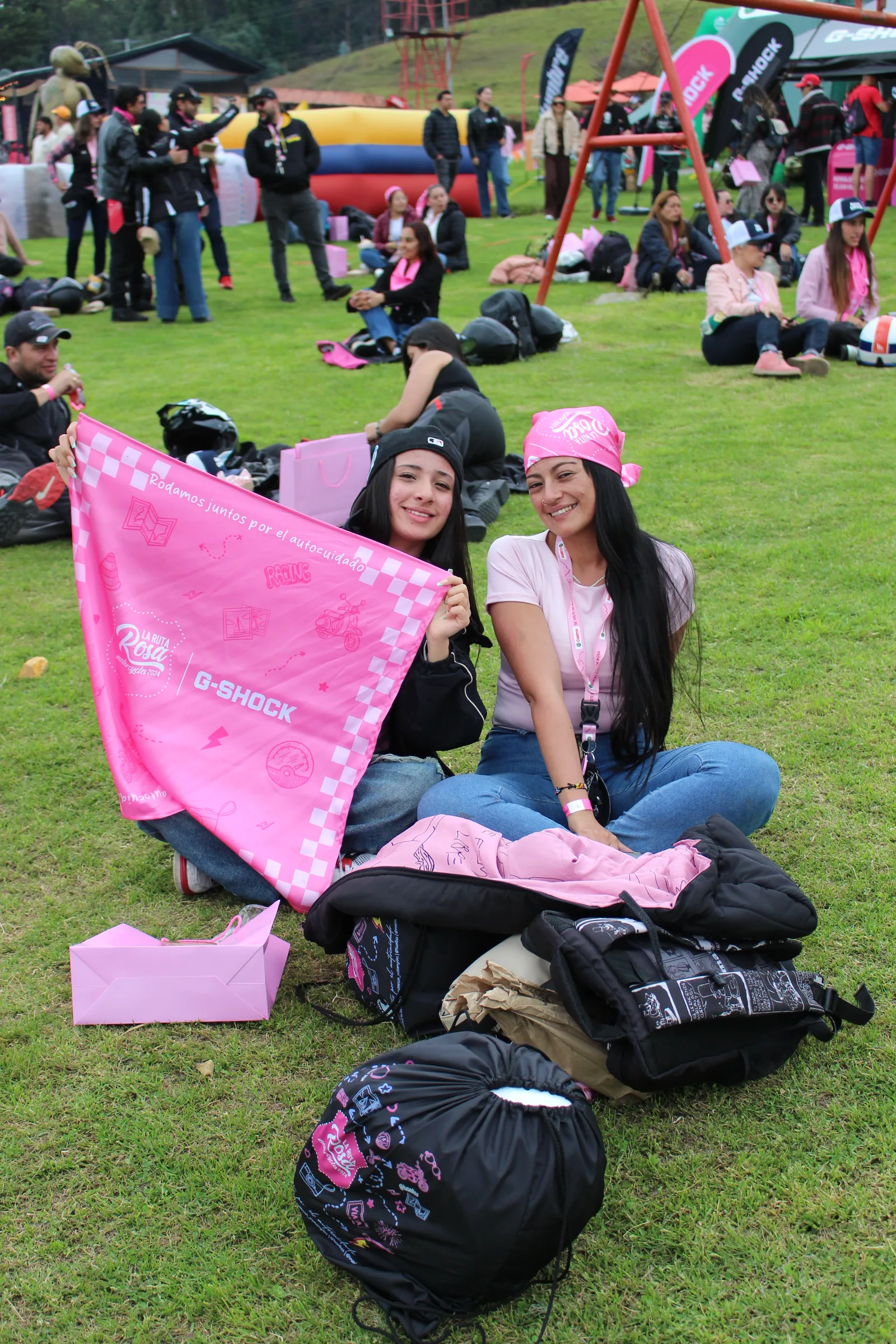 Dos participantes comparten una pañoleta rosa durante el encuentro sobre el césped.