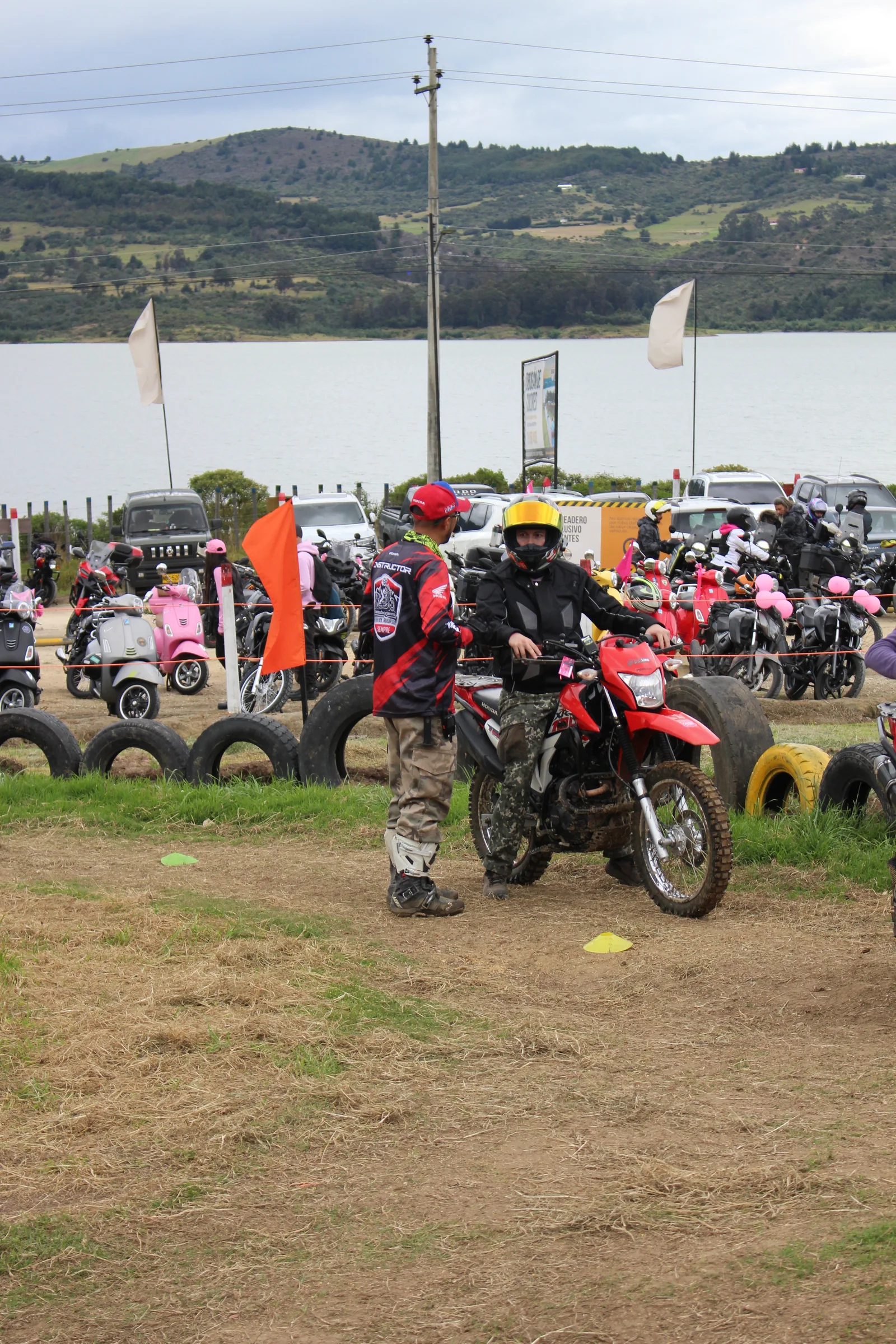 Motociclistas en la zona de actividades junto al embalse, con las motos de la comunidad al fondo.